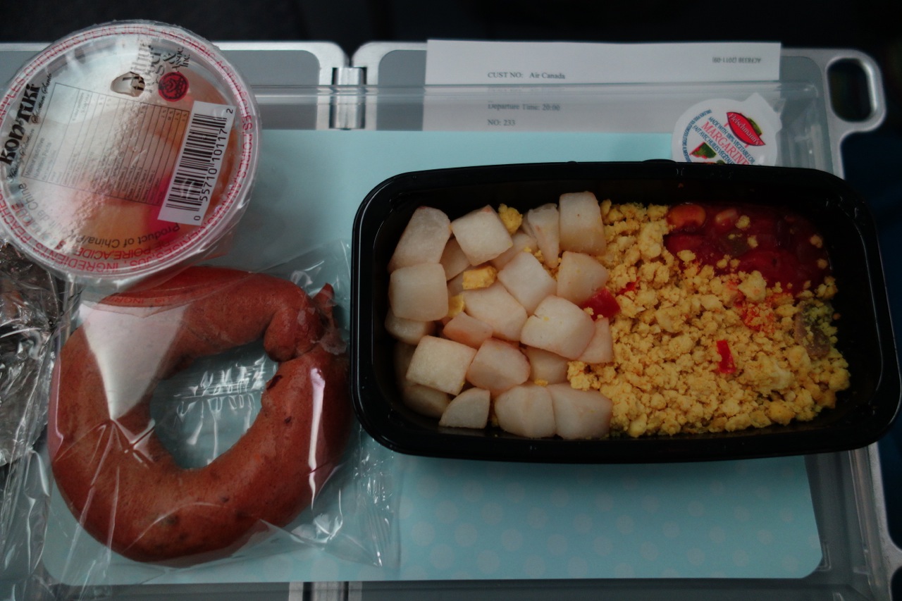 Breakfast of rubbery tofu scramble, potatoes, dry bagel, and fruit cup made in China