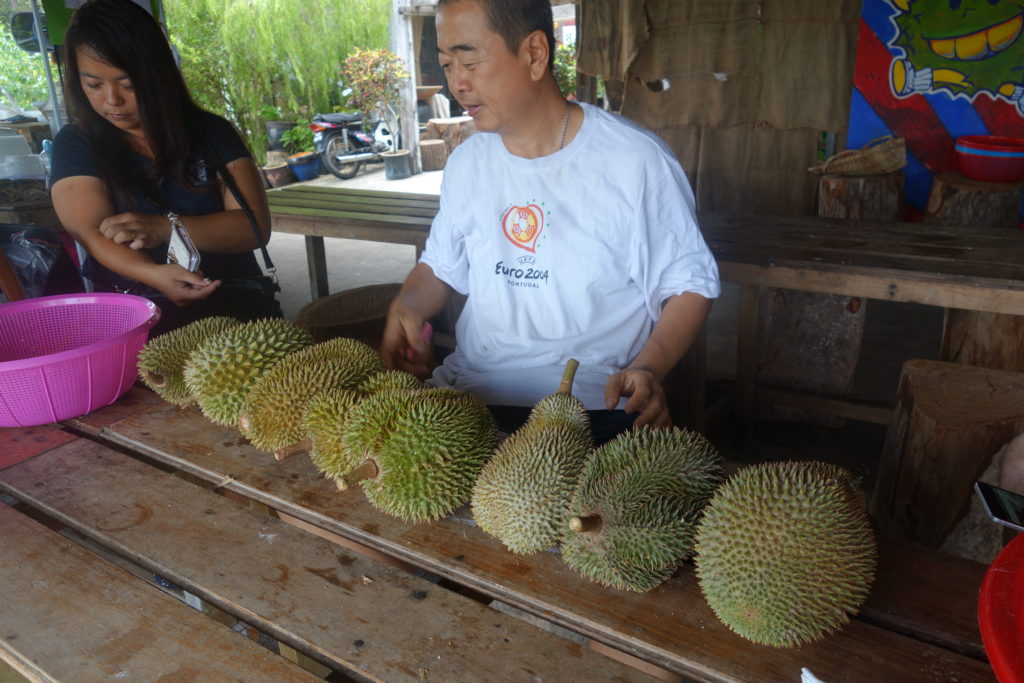a man sitting at a table with several durian fruits