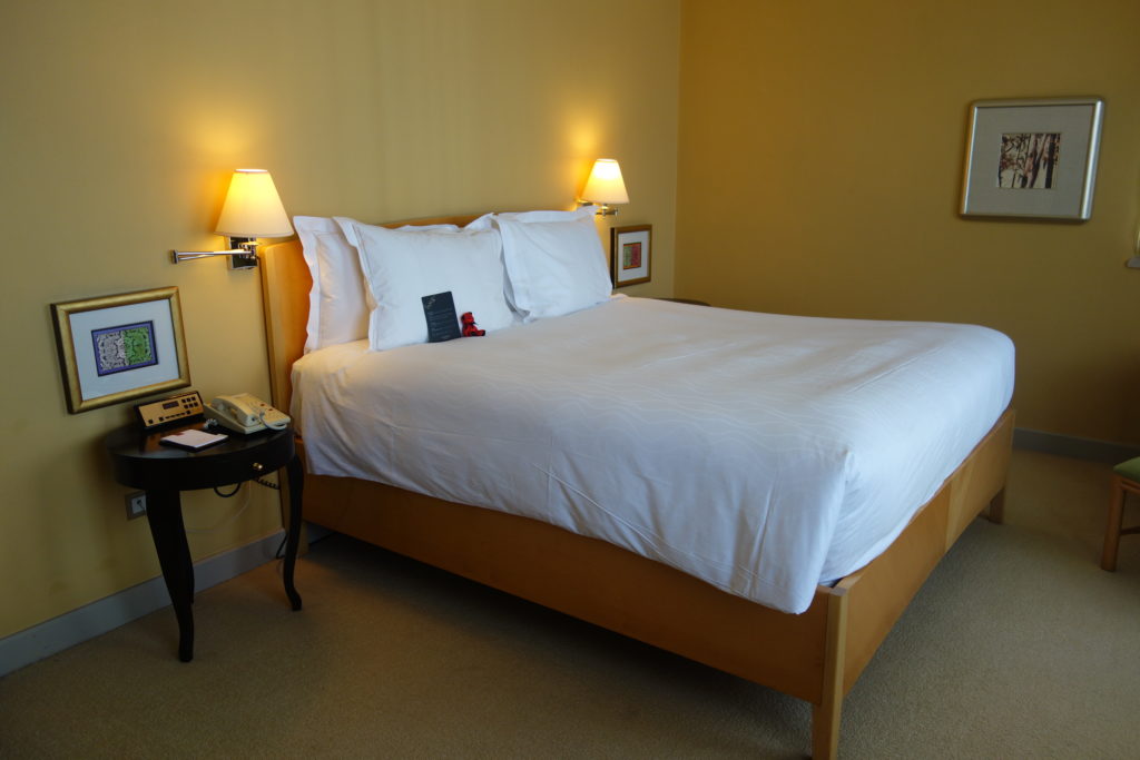 a bed with white sheets and a telephone on the side table