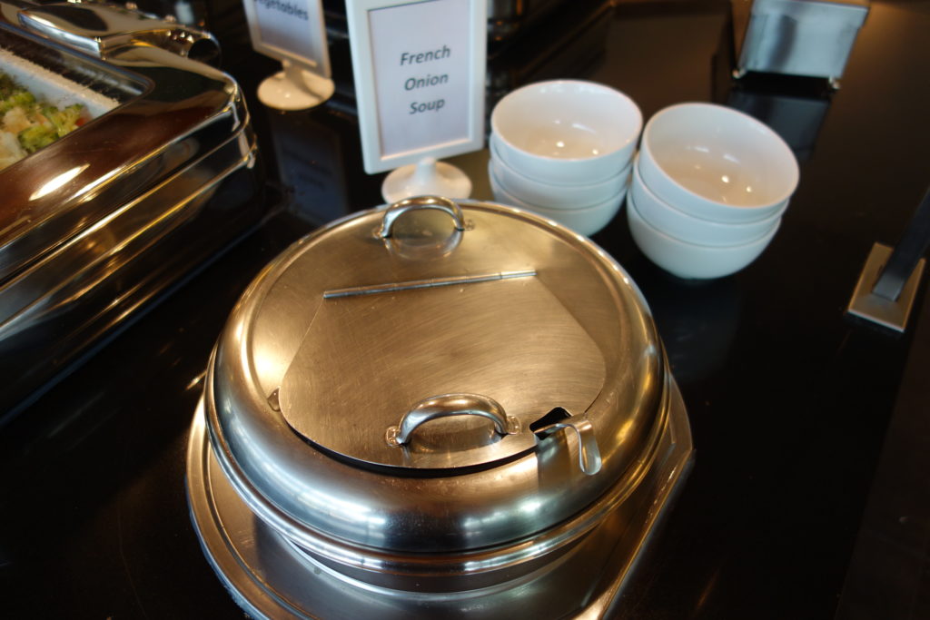 a silver container with a lid on a table with white bowls