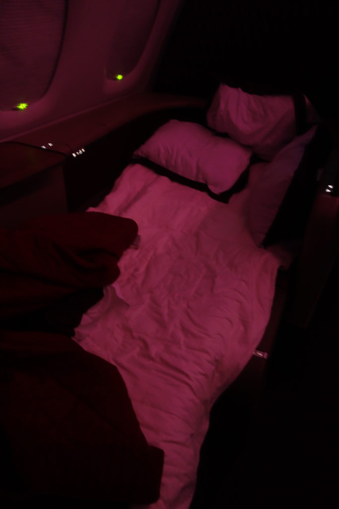 a bed with pillows and blankets in a dark room