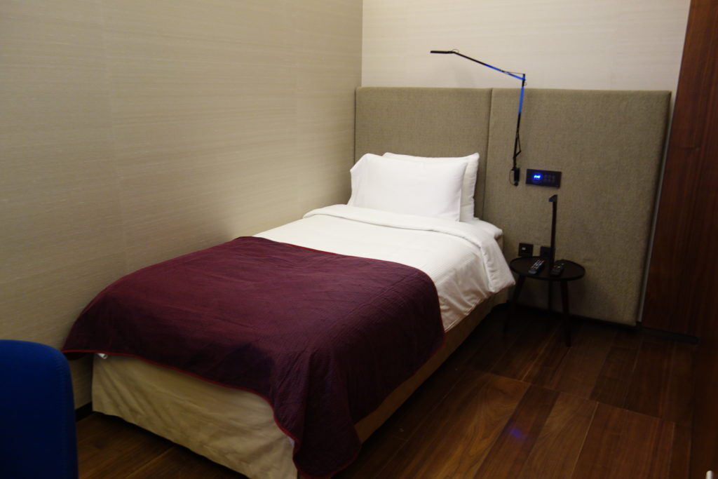 a bed with a purple blanket and a lamp on the headboard