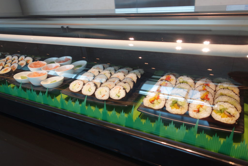 a display case with sushi rolls and other food
