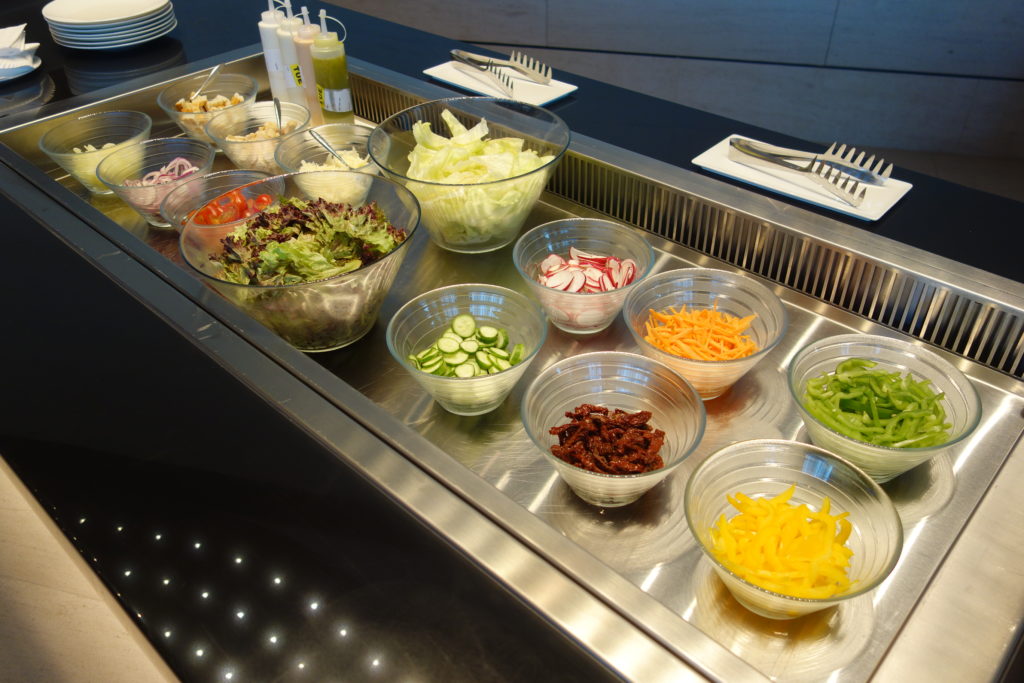 a salad bar with bowls of vegetables and other food