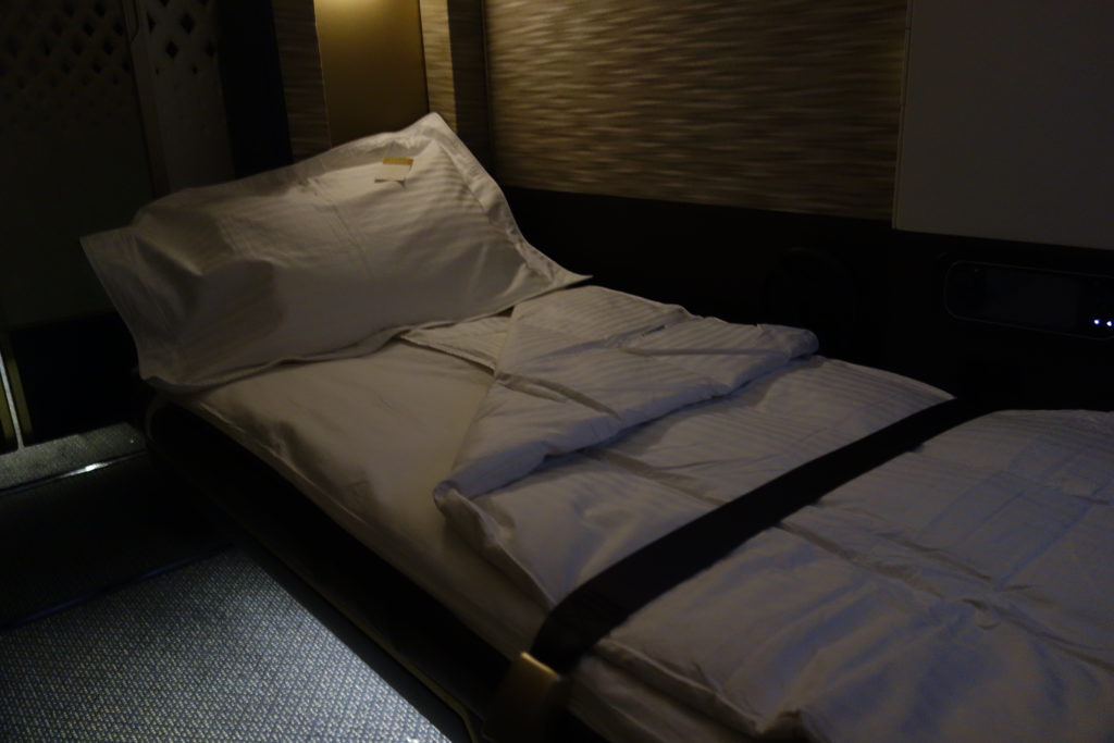 a bed with white sheets and a black belt