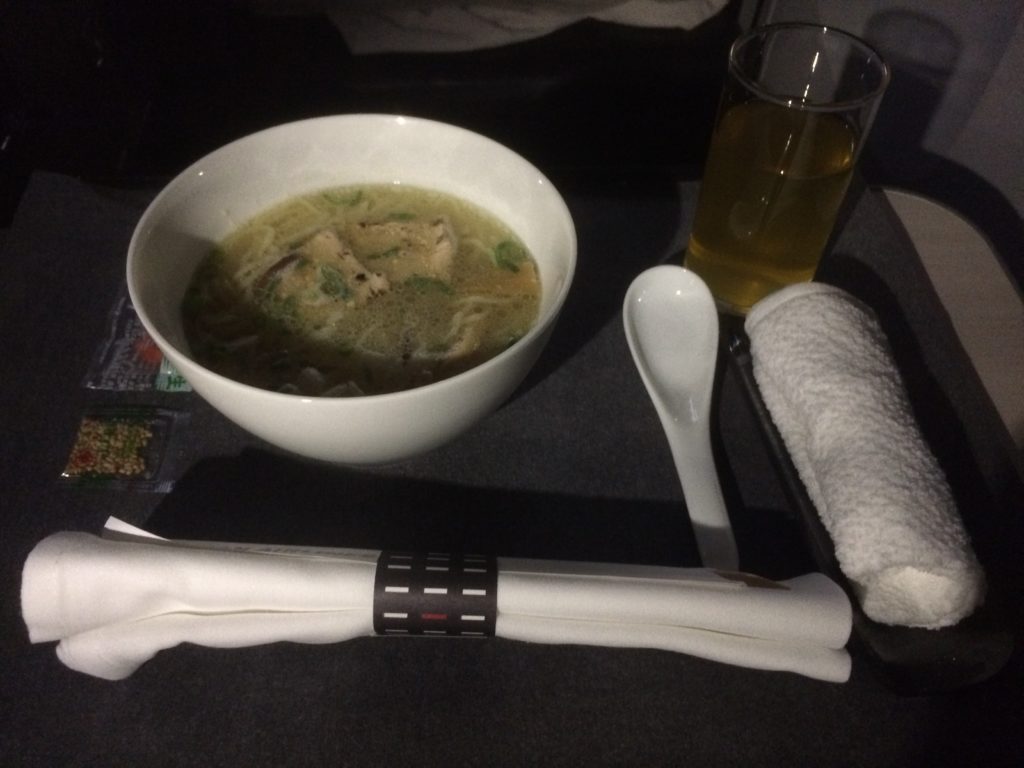 a bowl of soup and a glass of liquid next to a spoon and napkin