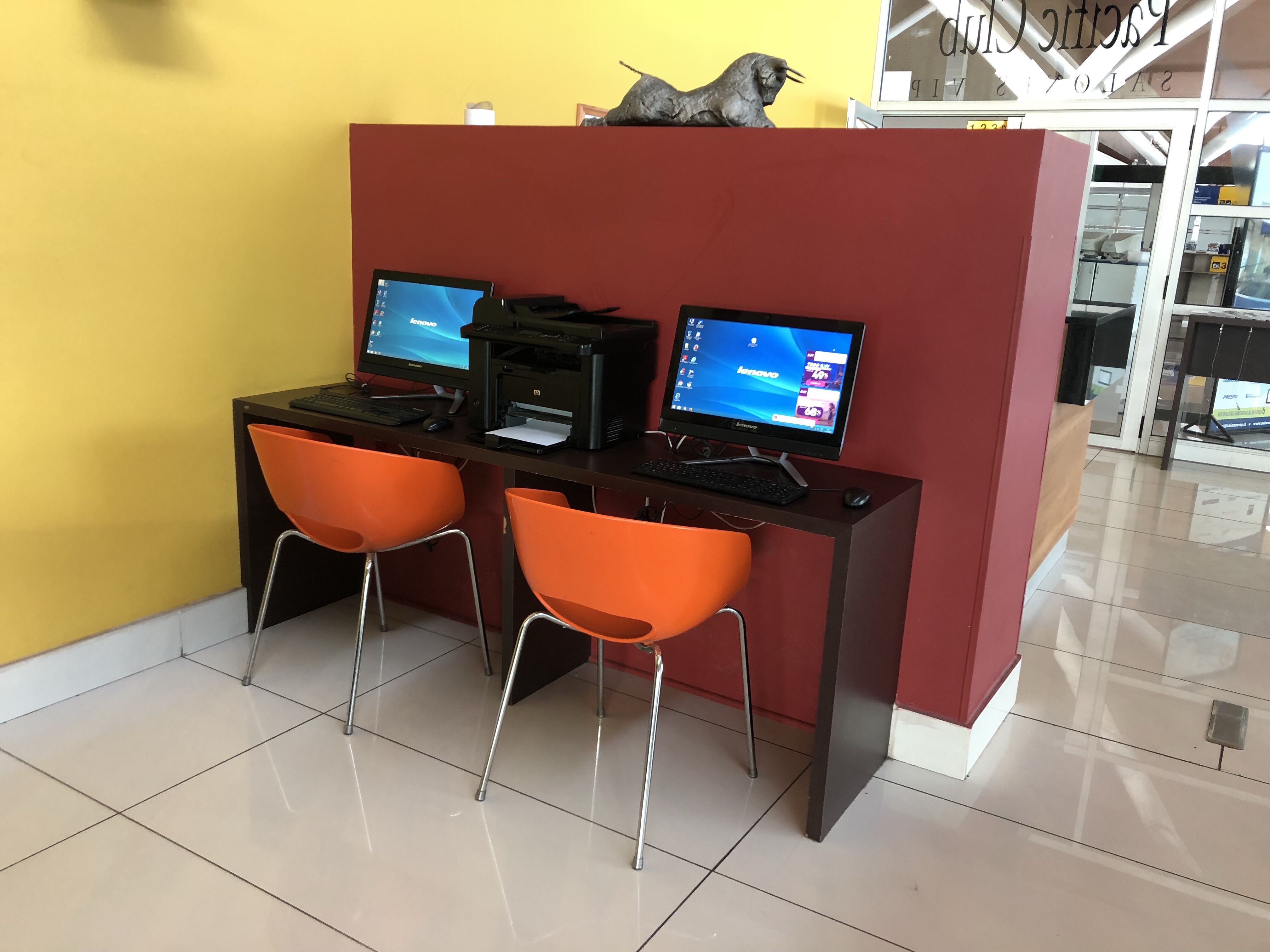 a desk with computers and orange chairs